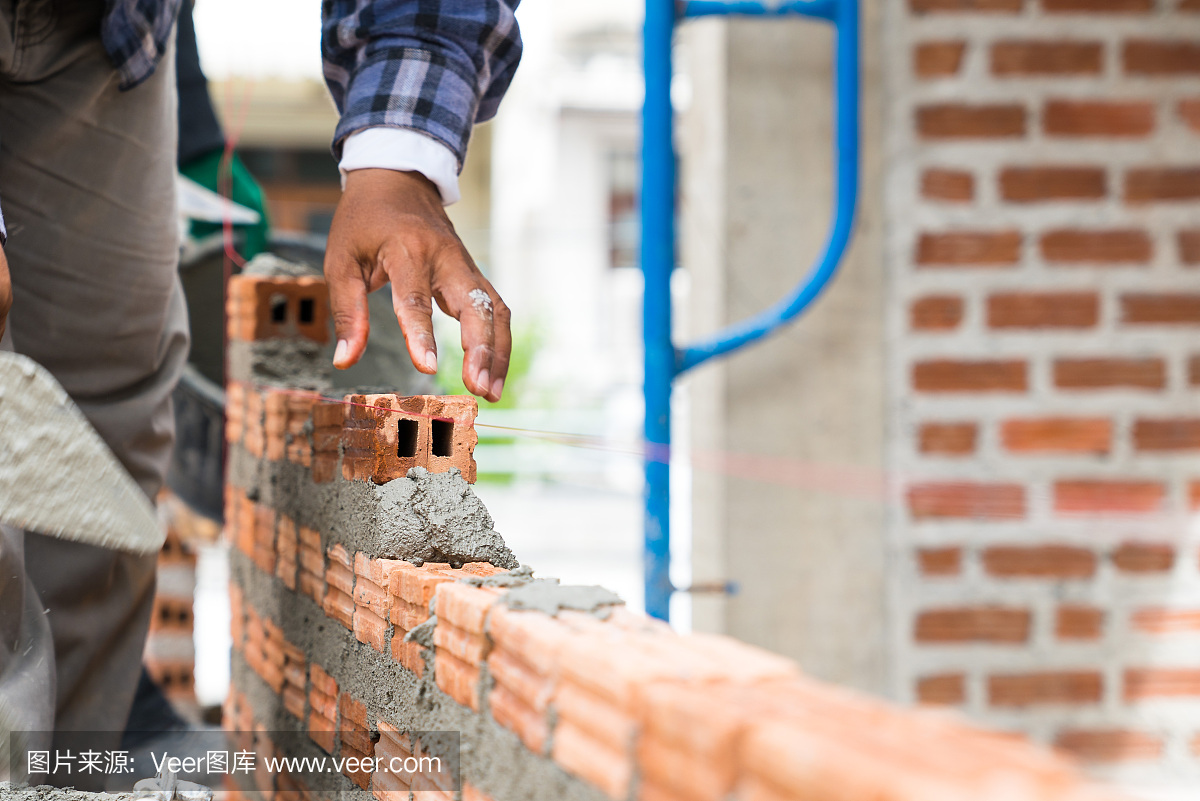 砖墙,技术人员正在用灰浆(水泥、沙子)形成砖墙,在工程房屋建设中使用镘作为工具